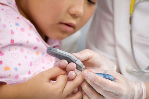 doctor showing child how to use a glucose meter