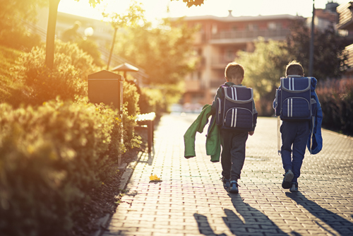 two young boys walking home from school with backpacks on