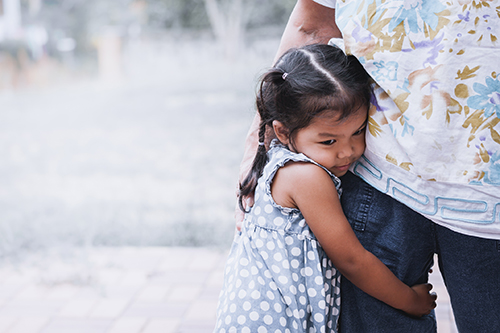 little girl holding mothers leg