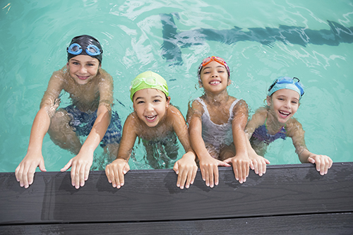 young boys and girls holding onto the edge of a pool