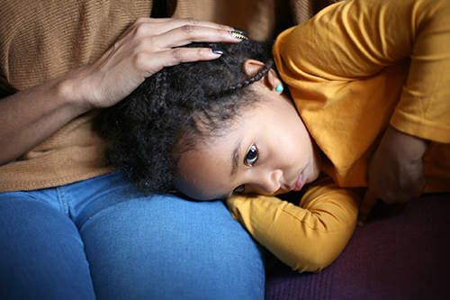 young girl with her head on her mothers lap