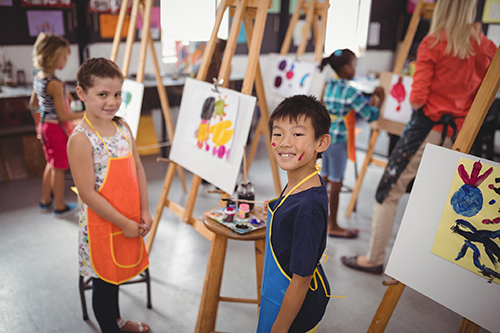 Little girl and boy painting in art class