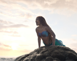 Halle Bailey as Ariel singing on rock in Disney's Live Action Little Mermaid