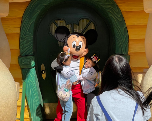 Two girls taking photos with Mickey during their visit to Disneyland's Toontown
