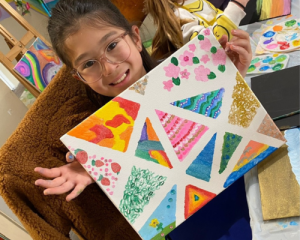 Little Girl shows off her colorful triangle artwork at Art Therapy OC