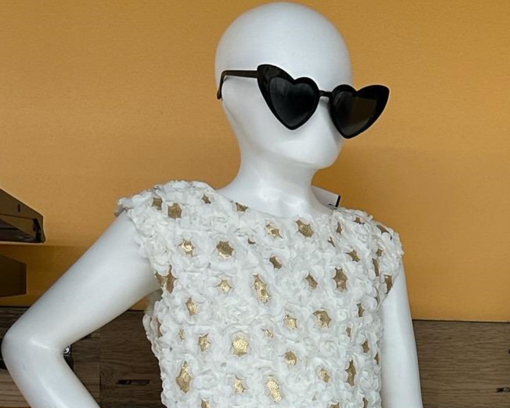 A Taylor Swift Halloween costume styled with heart-shaped sunglasses and a white floral patterned short sleeve shirt