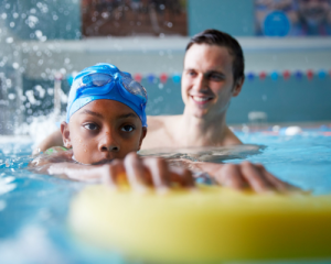 kid learning to swim from instructor